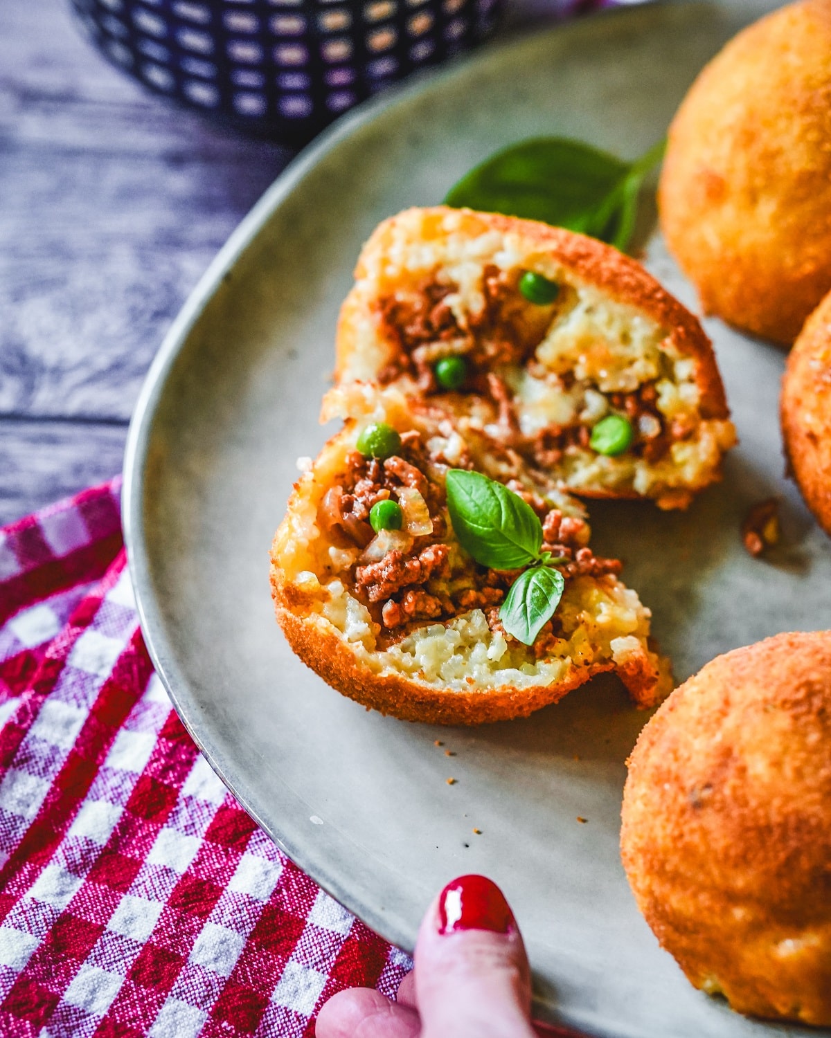 Gefüllte Arancini mit Hackfleisch, Mozzarella und grünen Erbsen auf Teller serviert.