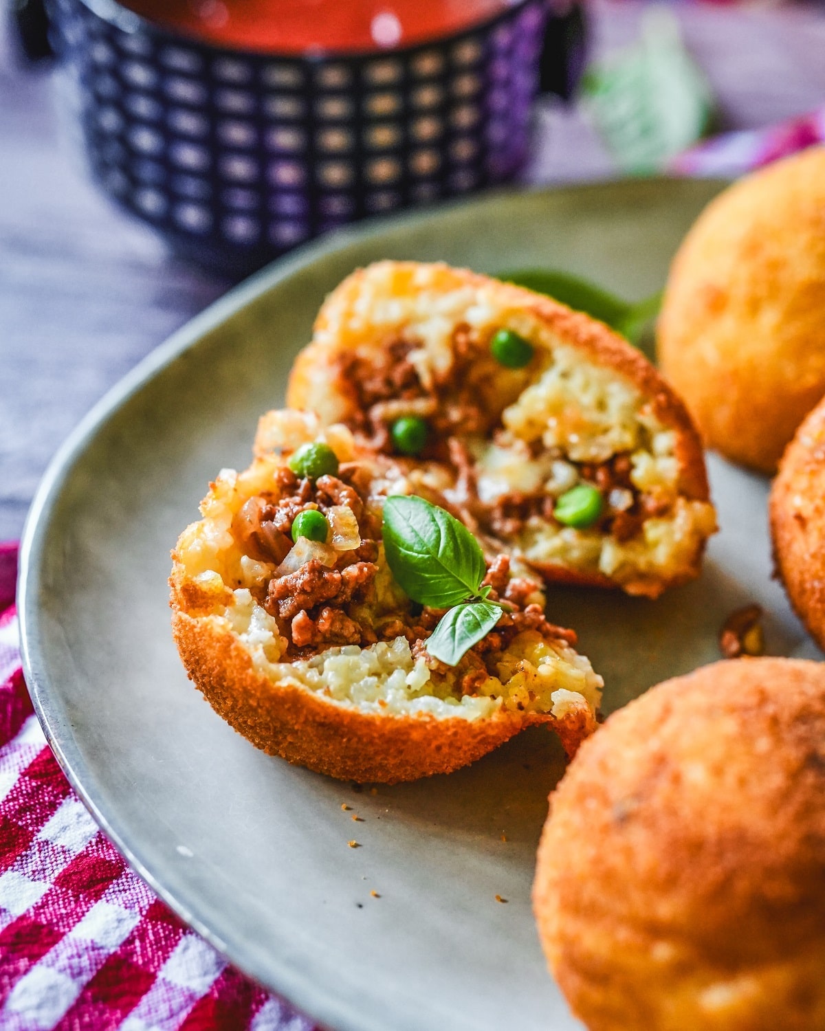 Gefüllte Arancini mit Hackfleisch, Mozzarella und frischen Kräutern auf Teller serviert.