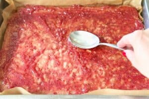 Fingerlickenkuchen-Teig wird mit einem Löffel auf dem Backblech verteilt und glattgestrichen.