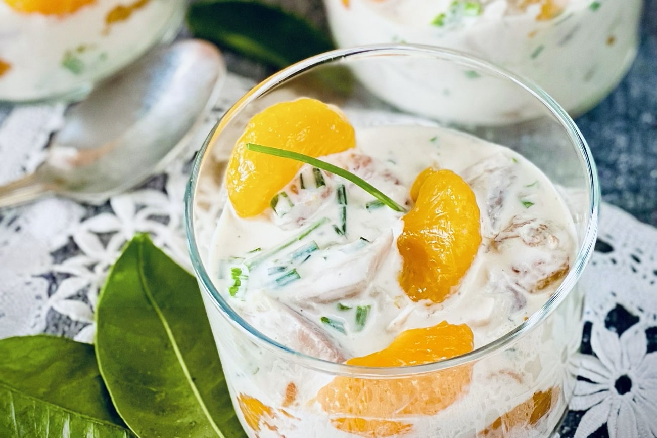 Geflügelsalat mit Mandarinen und Schnittlauch in Gläsern serviert, cremig und frisch garniert.