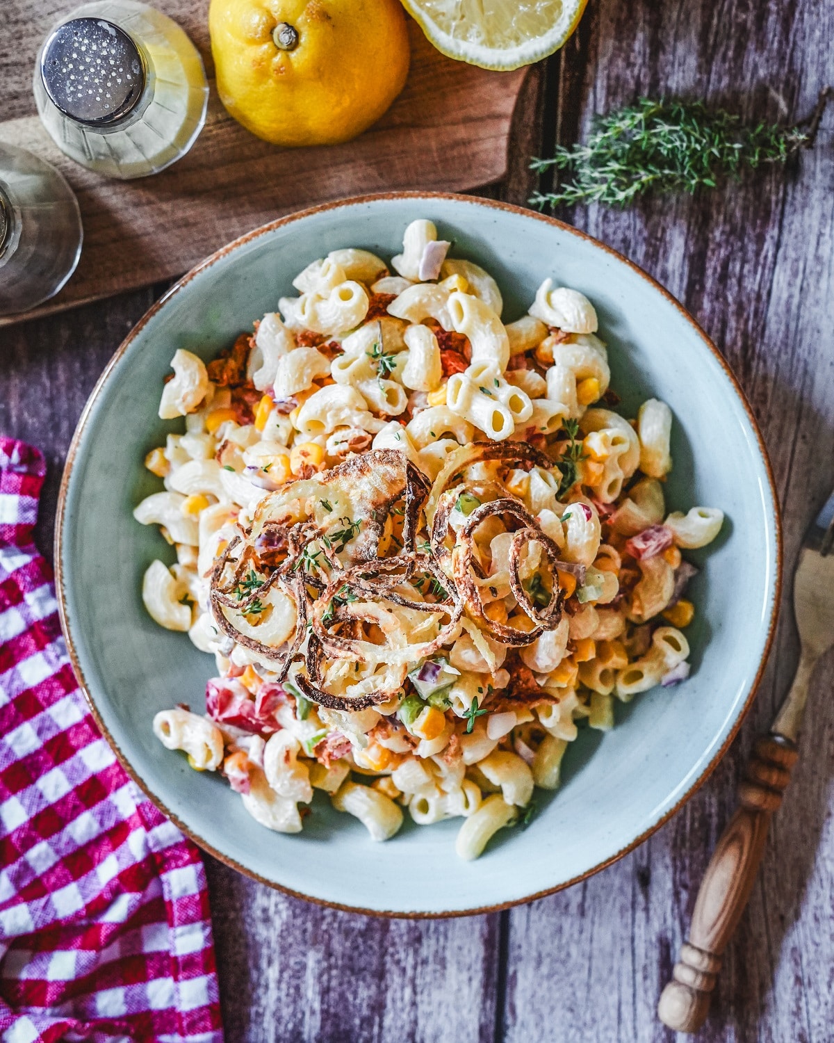 Schwedischer Nudelsalat mit cremigem Dressing, Speckstreifen und crispy Zwiebeln in einer Schale serviert.