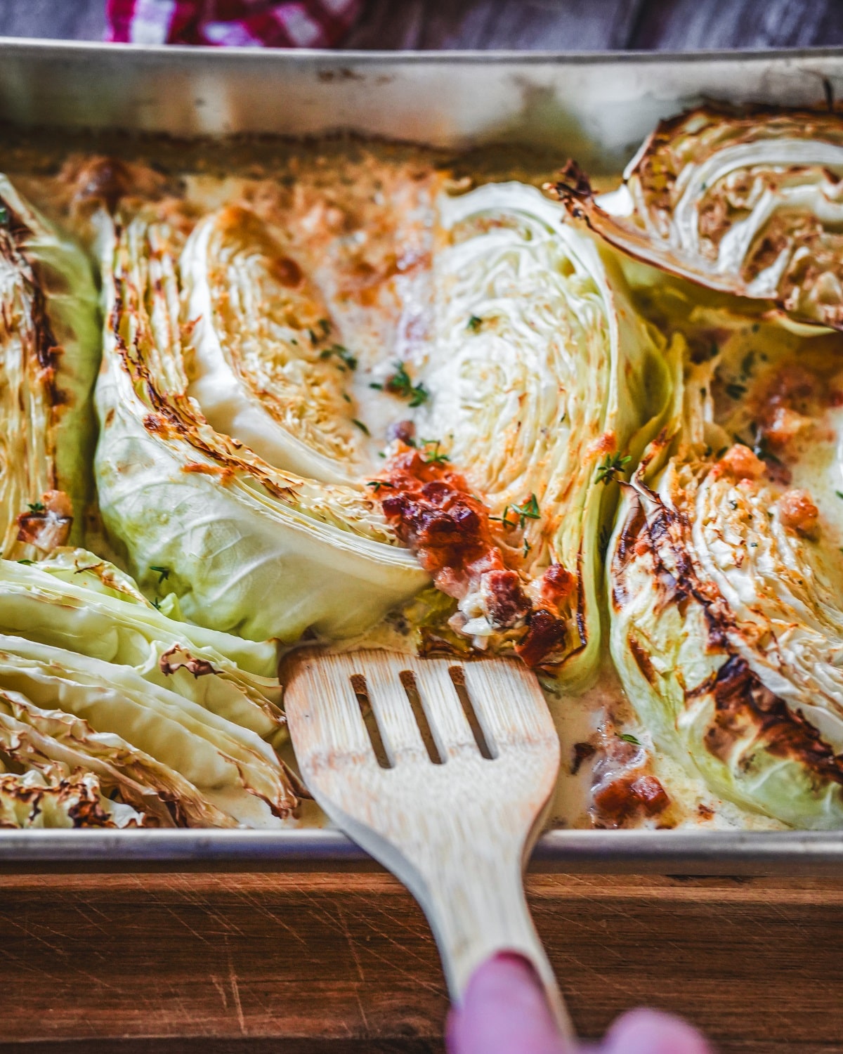 Gerösteter Spitzkohl mit Speck und Parmesan auf Backblech, mit Holzschieber.