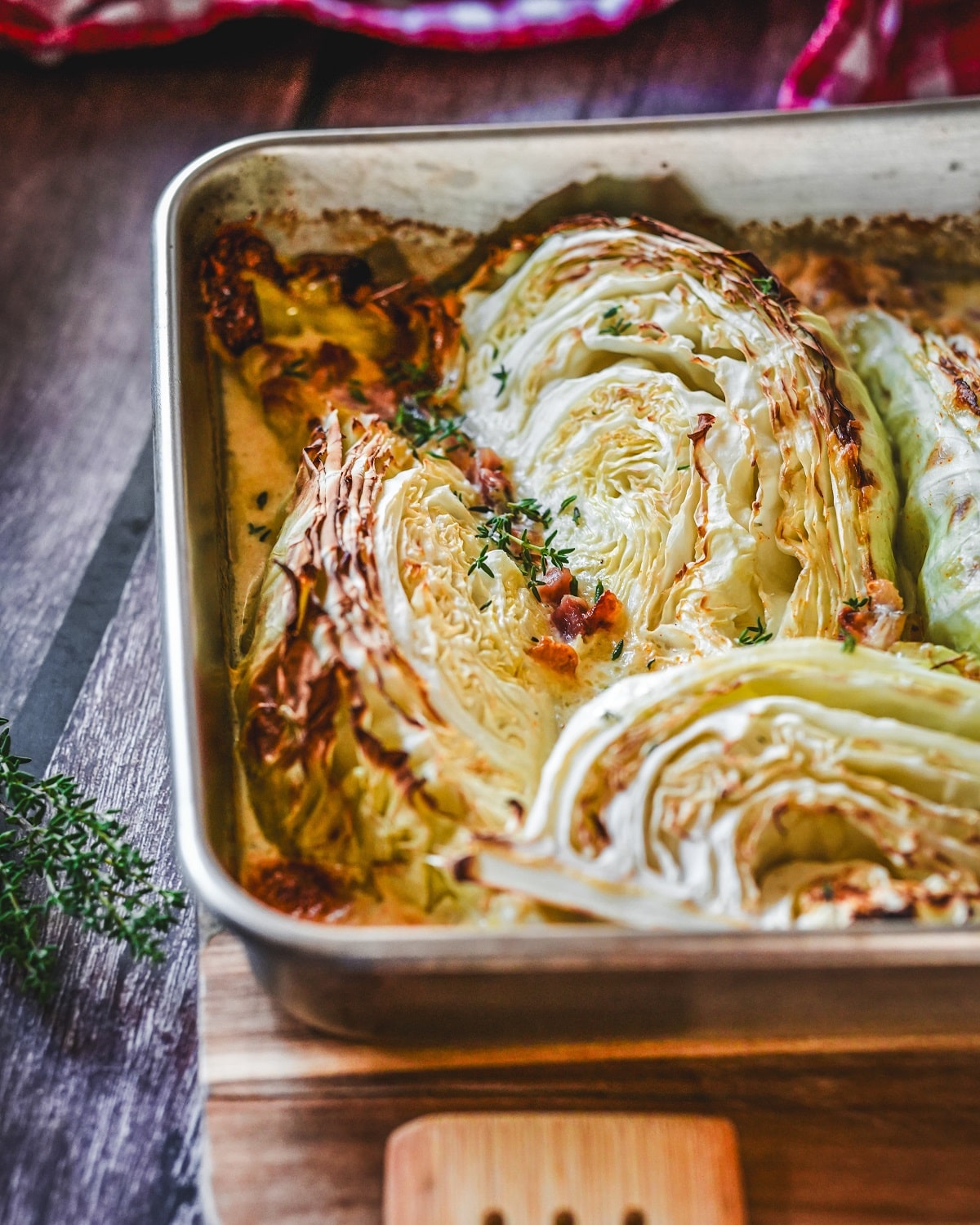 Gerösteter Spitzkohl mit Speck und Parmesan im Backblech, garniert mit frischen Kräutern.