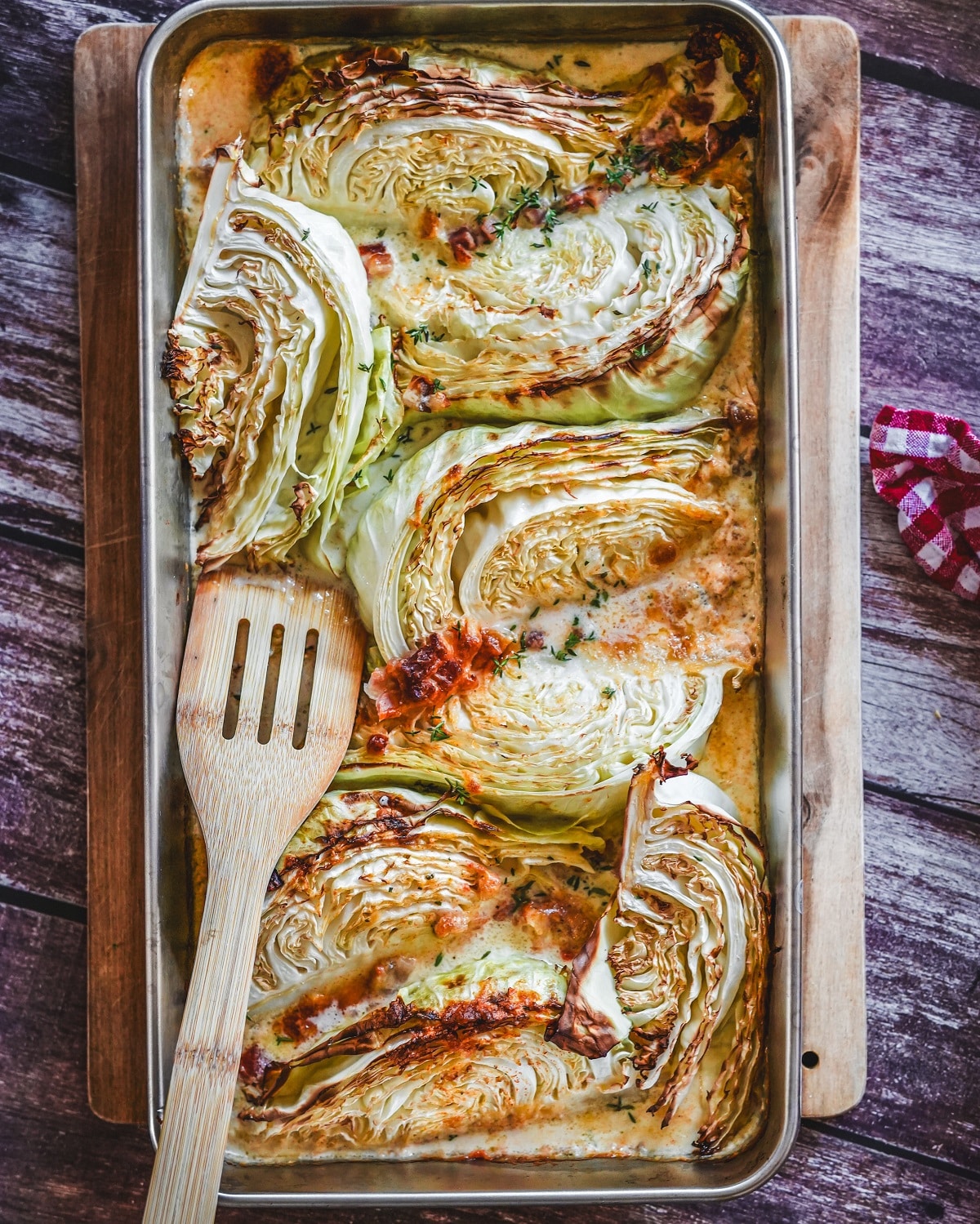 Gerösteter Spitzkohl mit Speck und Parmesan in Backblech, garniert mit Kräutern.