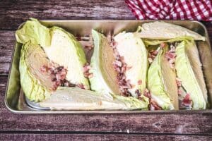 Spitzkohl aus dem Ofen mit Speck in einer Auflaufform kurz vor dem Übergießen mit Sahnesoße zum Schmoren im Ofen.