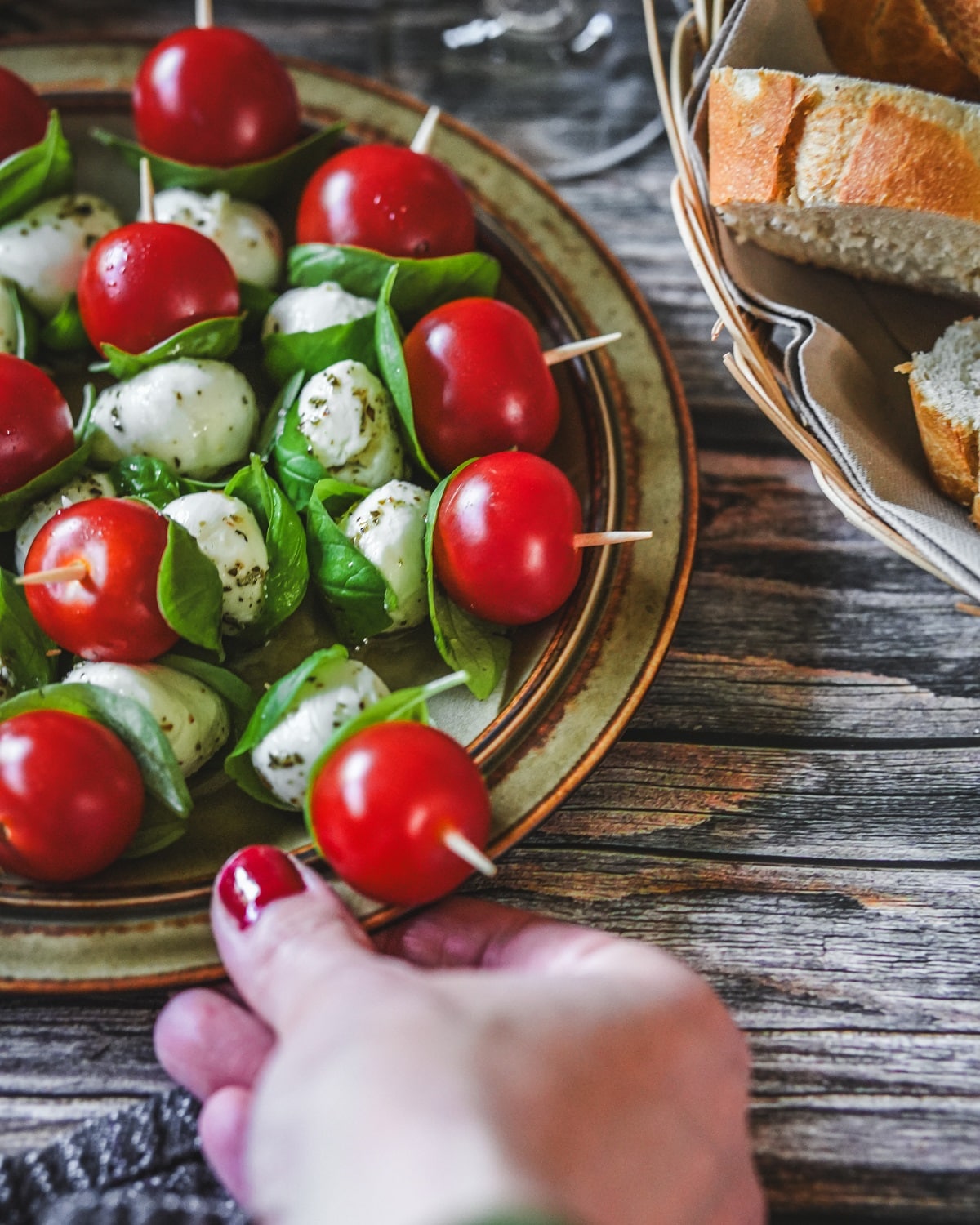 Tomate-Mozzarella-Spieße mit Basilikum auf Teller, serviert mit Brot