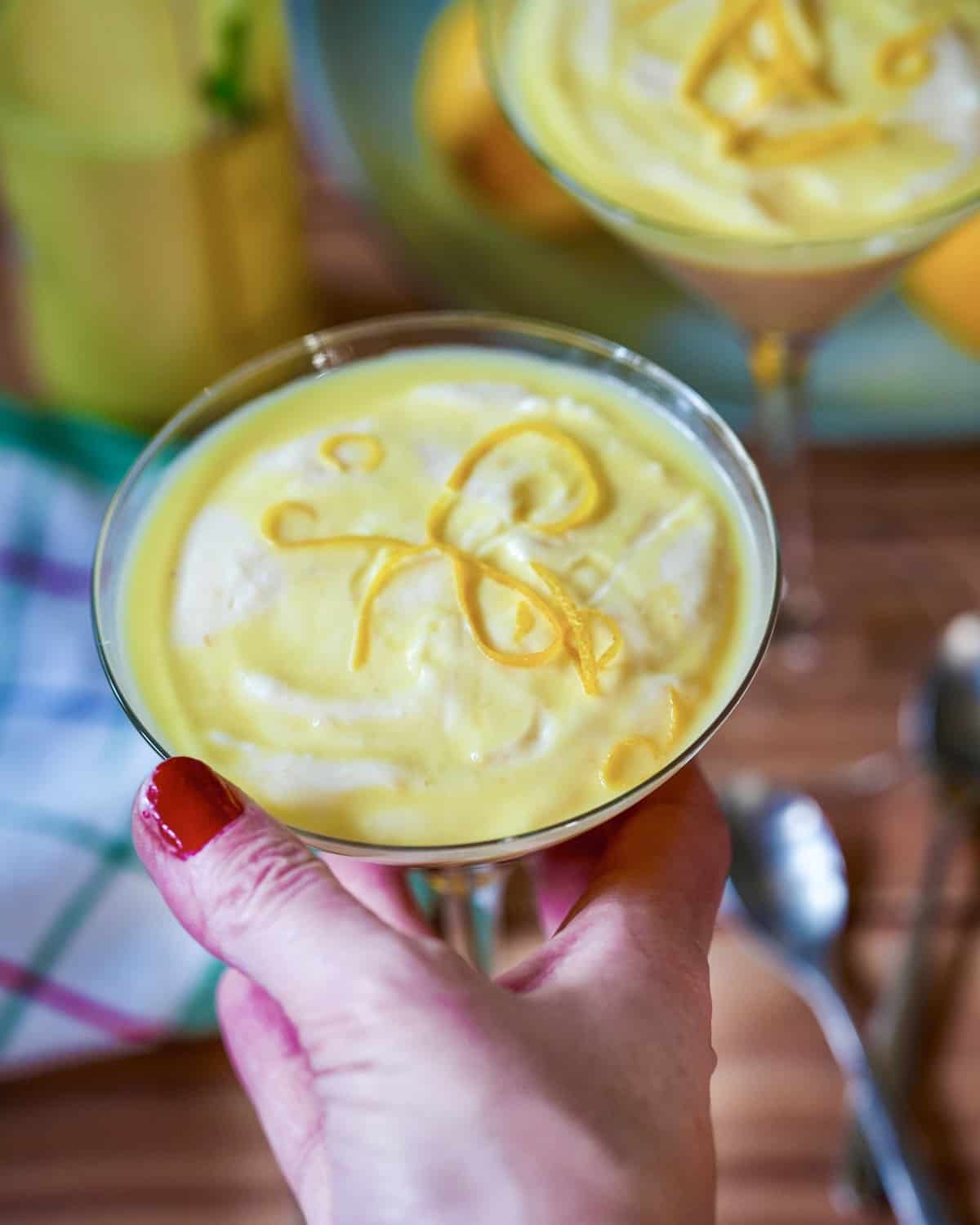 Zitronencreme mit Zitronenschale garniert, cremige mediterrane Dessertcreme im Glas.