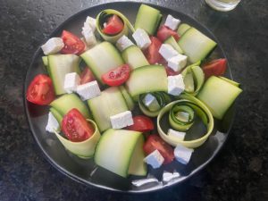 cocktail tomaten und feta ueber zucchinisalat verteilt