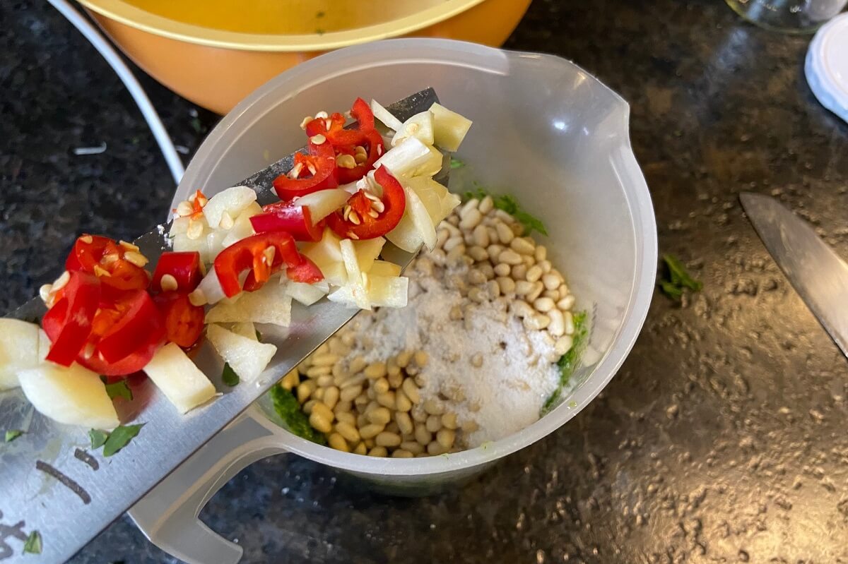 geschnittene chilischote und knoblauch zum puerierten rucola geben