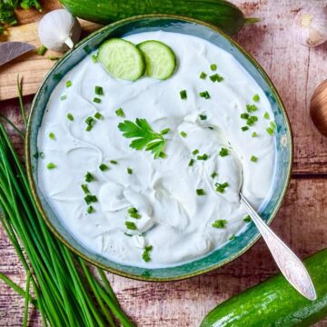 Gurken-Kräuter-Dip mit Schnittlauch und Petersilie, serviert in Schüssel mit frischen Zutaten.