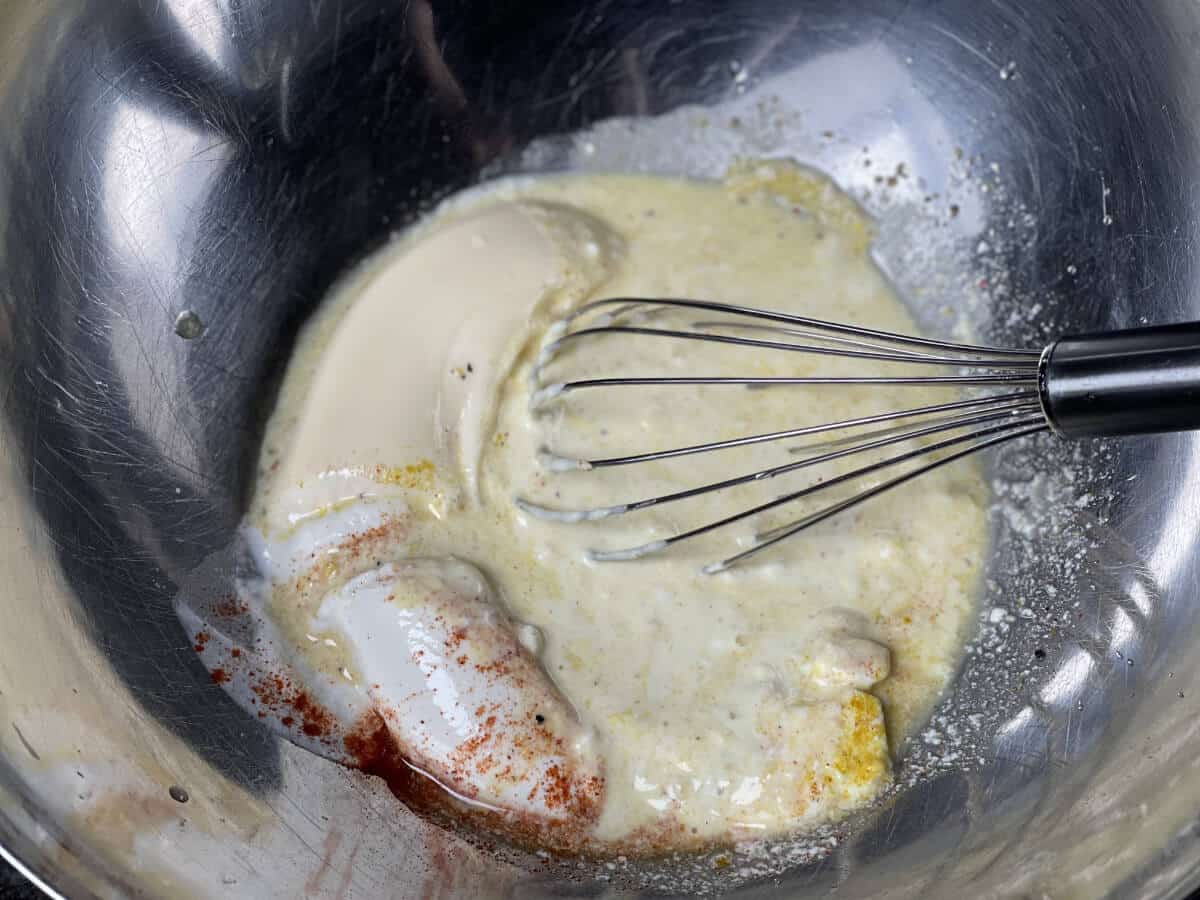 mayonnaise, senf, saure sahne, gurkensud und gewuerze in schuessel verruehren
