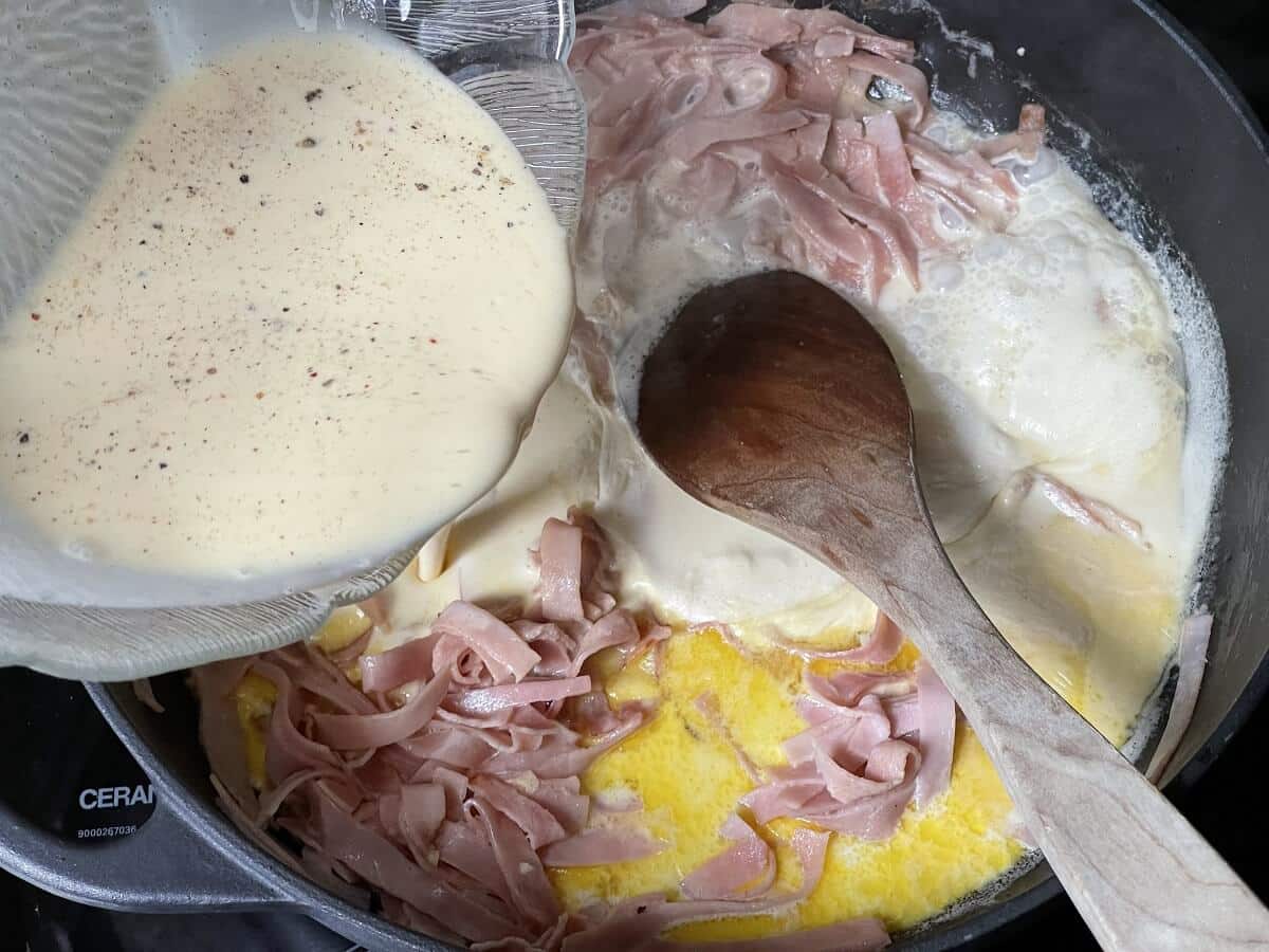 sahne ei mischung zu angeschwitzem schinken in die pfanne geben