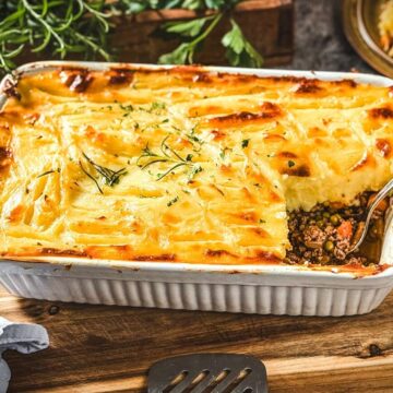 Shepherd's Pie mit goldbrauner Kartoffelpüree-Kruste, garniert mit Rosmarin in Auflaufform.