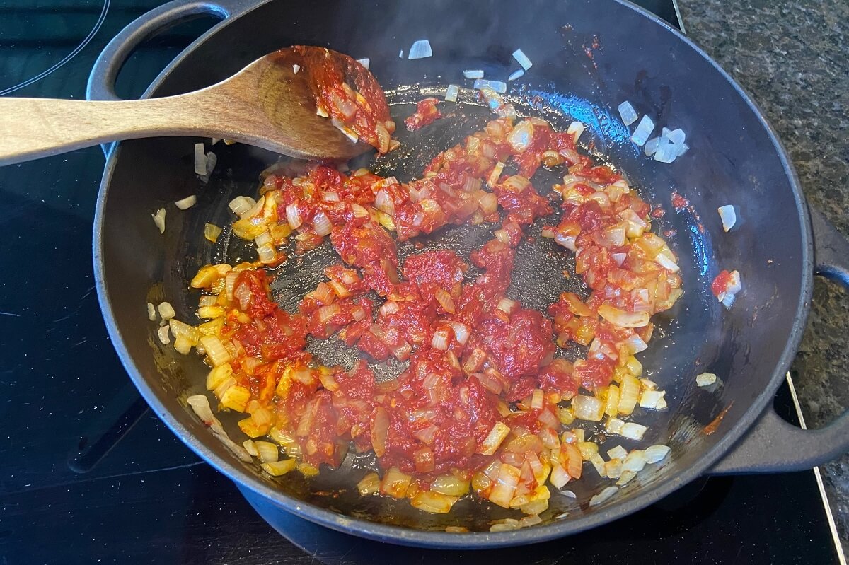 tomatenmark zu angeschwitzem knoblauch und zwiebeln in die pfanne ruehren